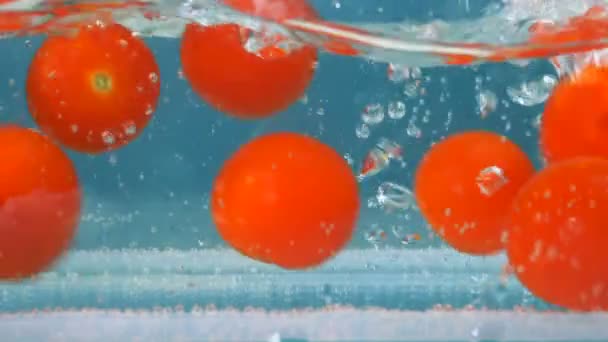 Tomaten vallen in blauwe zoet water. Hoge snelheidscamera schot. — Stockvideo