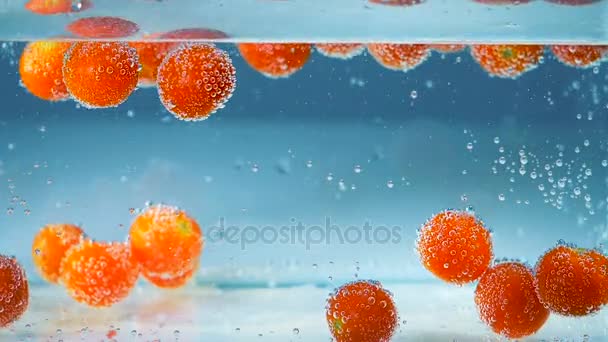 Abstrakter Hintergrund. Rote Tomaten in blauem Wasser gehen hoch und runter. — Stockvideo