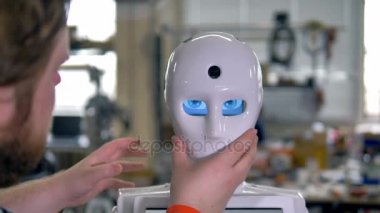 Bir mühendis beyaz bir maske robotlar yüzüne koyar..