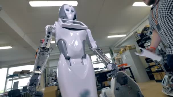 Een jonge reparateur dekt robots stalen frame op de onderarmen. — Stockvideo