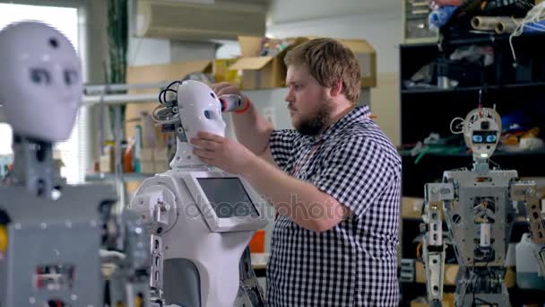 Um engenheiro corrige a máscara de robôs . — Vídeo de Stock