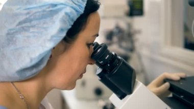 Mikroskoplar göz mercekleri arayan bir kadın üzerinde Görünümü Kapat.