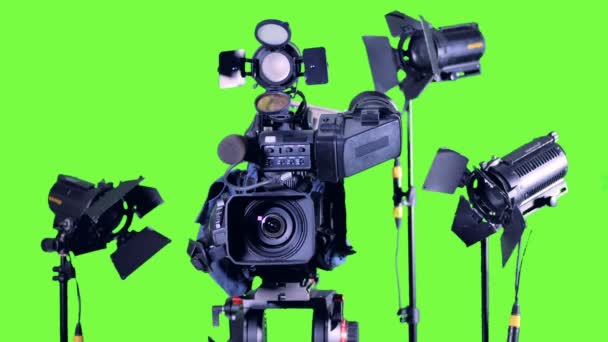 Heldere schijnwerpers staan in de buurt van professionele videocamera op een groen scherm. — Stockvideo