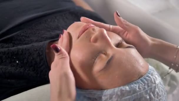 Una esteticista masajea la cara de sus clientes después del tratamiento de belleza . — Vídeo de stock