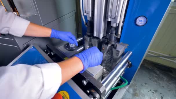 Een werknemer installeert preforms in een geribbelde klap-molding machine. — Stockvideo