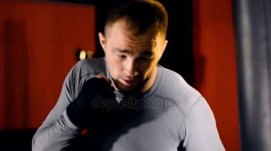 Bir boksör boks çanta üzerinde ağır yumruk atar.