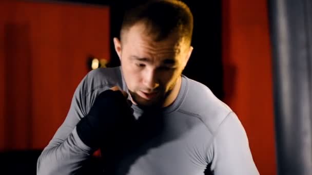 Um boxeador dá socos pesados em um saco de boxe . — Vídeo de Stock