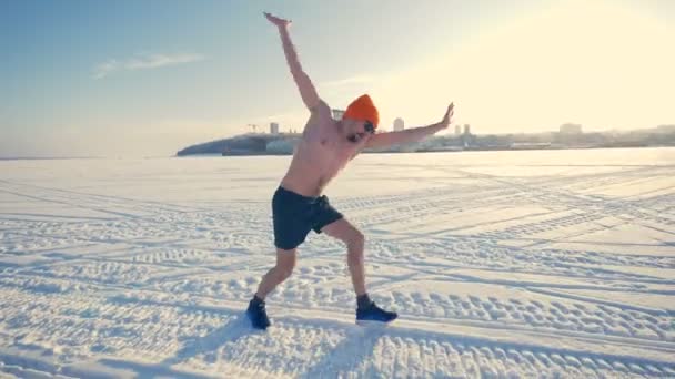 Un homme à poitrine nue fait un mouvement de roue sur la neige . — Video