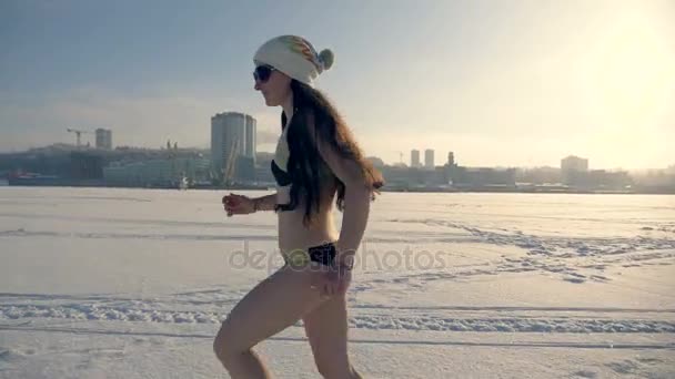 Eine Frau rennt im Schnee über einen zugefrorenen Fluss. — Stockvideo