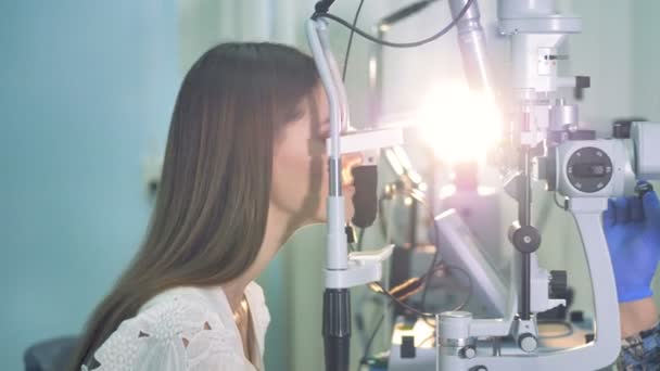 Een oogarts begint een examen op een jonge vrouw in de kliniek. — Stockvideo