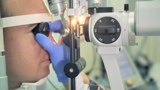 Un óptico sostiene una lente para examinar la parte posterior del ojo del paciente . — Vídeo de stock