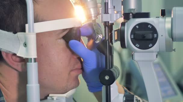 Gli oftalmologi le mani in guanti tengono una lente a un occhio di pazienti . — Video Stock