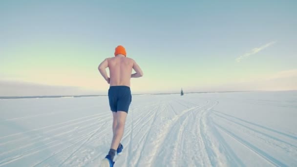 Ein Athlet rennt im Schnee auf den Horizont zu. — Stockvideo