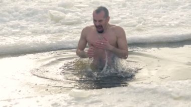 Bir buz delik soğuk suda bir adam çıkar.