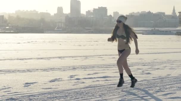 Uma mulher usando botas e um biquíni corre durante o inverno . — Vídeo de Stock