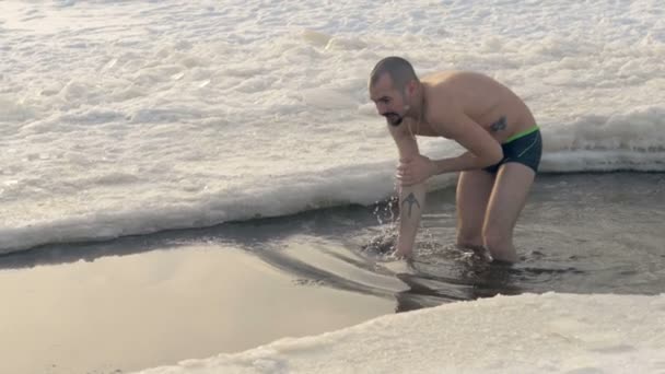 Un hombre entra en agua fría en un agujero de hielo . — Vídeos de Stock