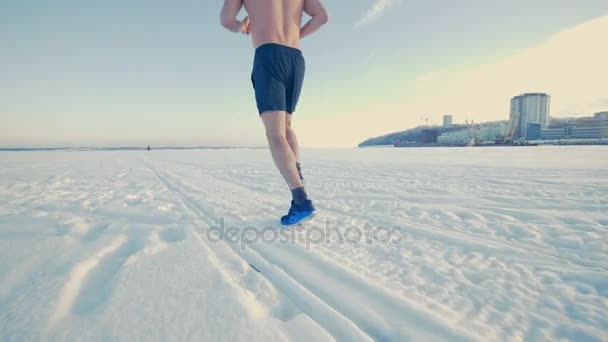 Ein Mann im Jogginganzug zeigt Joggen im Schnee. — Stockvideo