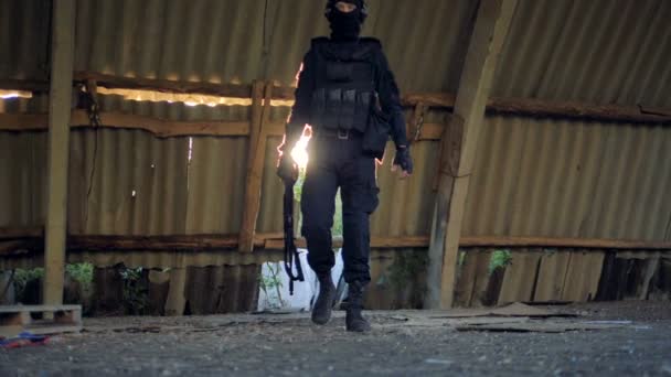 Gemächlich schreitet ein maskierter Kämpfer mit einem Gewehr in der Hand vor. — Stockvideo