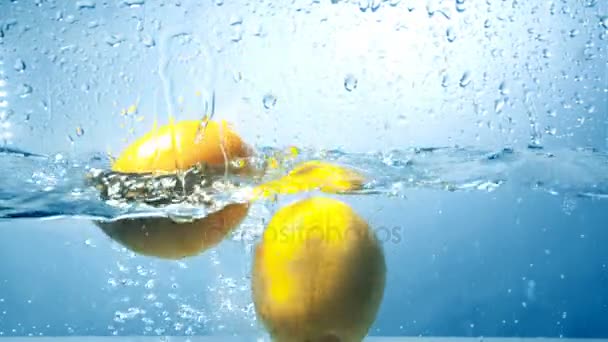 Trois citrons frais tombent dans l'eau en coup de contraste élevé . — Video