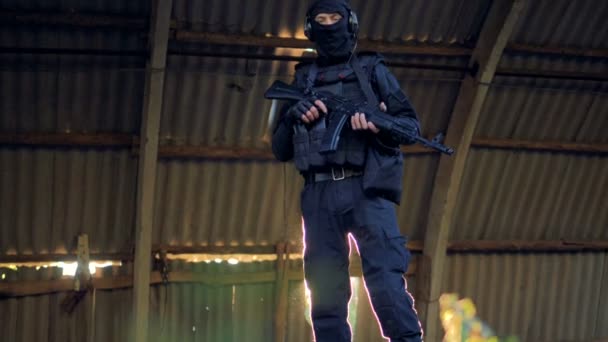 Ένα μέλος ΑE Swat στέκεται φορώντας ακουστικά και ένα φορτίο που μεταφέρουν γιλέκο. — Αρχείο Βίντεο