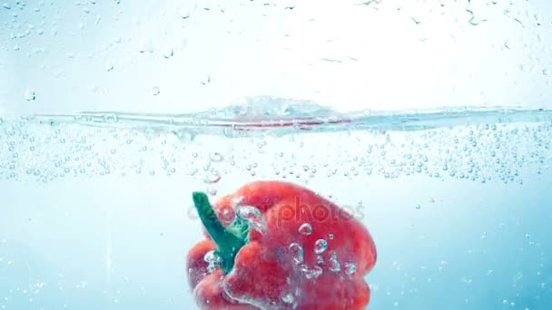 Un peperone rosso cade in acqua in un vaso di vetro . — Video Stock