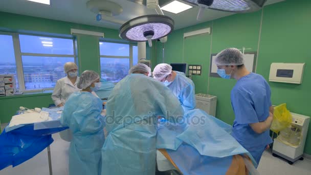 Νοσηλευτές και βοηθοί κρύψει τον ασθενή χειρουργική επέμβαση από την προβολή. — Αρχείο Βίντεο