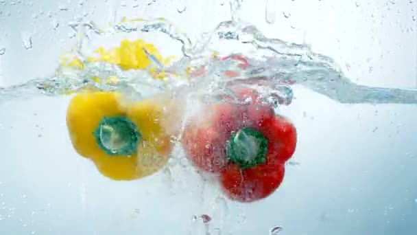 Dvě papriky spadnout do vody dohromady. — Stock video