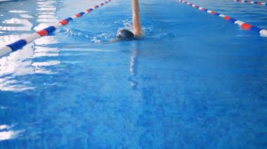Bir kadın bir havuzda sırtüstü yüzer.