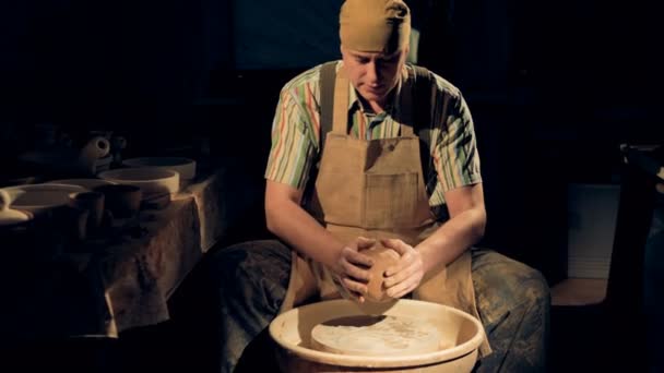 Een pottenbakker persen een grote clay bal op een aardewerk wiel. — Stockvideo