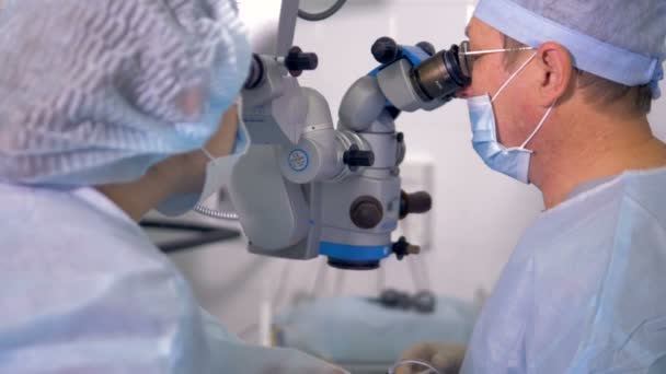 Deux chirurgiens examinent un microscope chirurgical professionnel . — Video