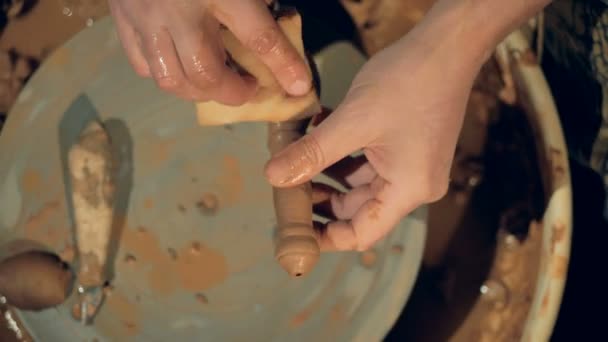 Ein Töpfer benutzt einen Schwamm, um einen Tonlöffel zu benetzen und zu reinigen. — Stockvideo