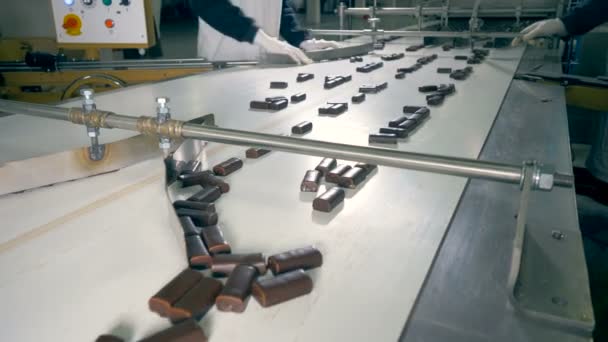 Chocolade snoepjes gaan verder na het verkrijgen van gesorteerd op twee fabrieksarbeiders in een close-up 4k. — Stockvideo