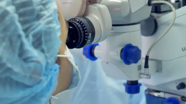 Le chirurgien cherche dans une oculaire d'une machine médicale pendant que l'autre opère — Video