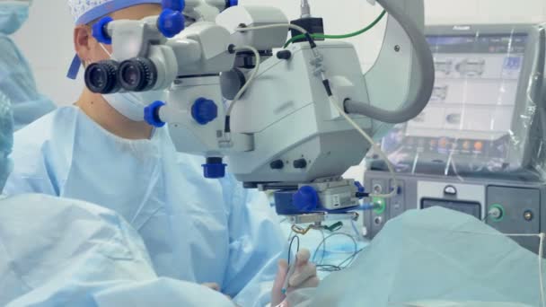 医生们在通过一台医疗机器观察它的同时执行手术。 — 图库视频影像