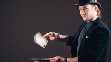 İllüzyonist havadan kağıtları almaktan ve onları üst kartları ile yapılan şapka atma.