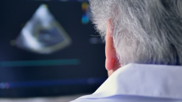 Cambio de la pantalla de ultrasonido con un médico masculino observándola — Vídeos de Stock