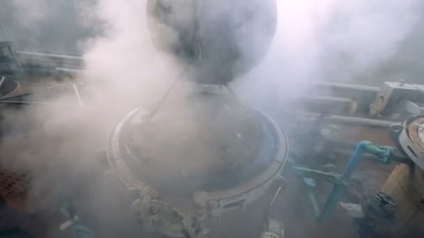Широка металева плита опускається в заводський котел з паровою водою — стокове відео