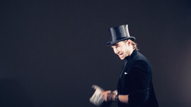 Un illusionniste masculin joue des tours de magie avec des cartes et les met ensemble dans un chapeau de carte — Video