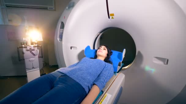 Une femme est allongée sur un lit de camp mobile d'une machine CT . — Video