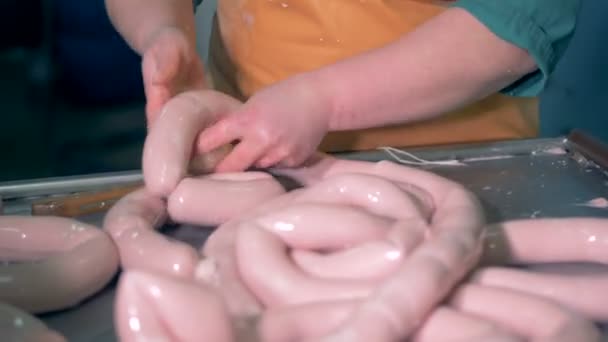 Un ouvrier d'usine lie toute une gamme de saucisses en petites. — Video