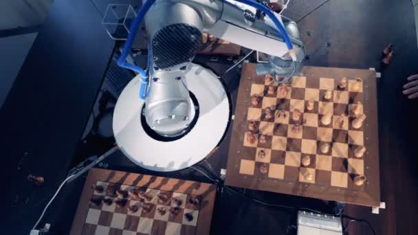 Un bras robotisé déplace des pièces d'échecs étant entouré de trois échiquiers — Video