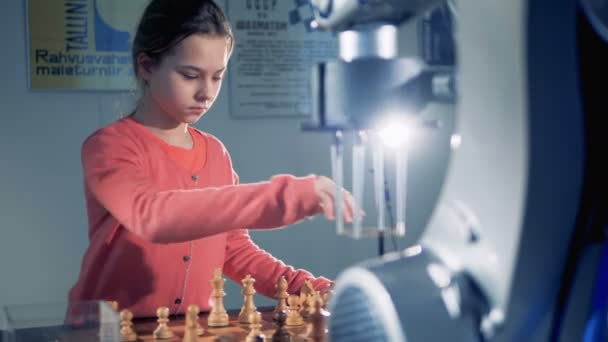 Ein kleines dunkelhaariges Mädchen spielt Schach mit einem Roboterarm — Stockvideo