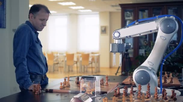 Side view of an adult man playing chess with a robotized arm — Stock Video