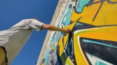 Grafiti sanatçısı duvardaki, görünümü sarı bir mektup aşağıdan boyama.