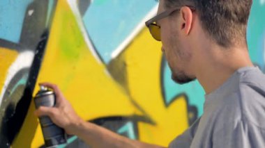 Grafiti sanatçısı duvardaki sarı mektup yanında siyah bir çizgi resim.