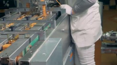 Fabrika işçisi işleminin kontrol ederken bitmiş bisküvi Konveyör bant hareket ediyor