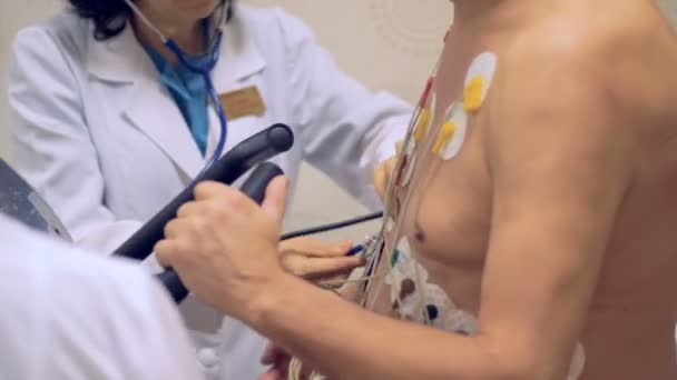 Heart diagnosis device on a patient. Doctor test patient vital parameters using attached electrodes on patients chest. — Stock Video