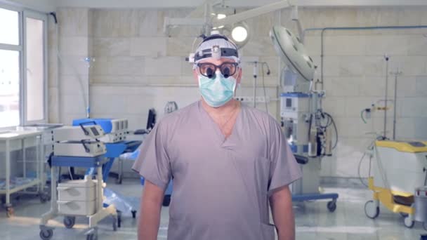 Retrato del médico senior con dispositivos médicos modernos de pie frente a la cámara en una cirugía . — Vídeos de Stock