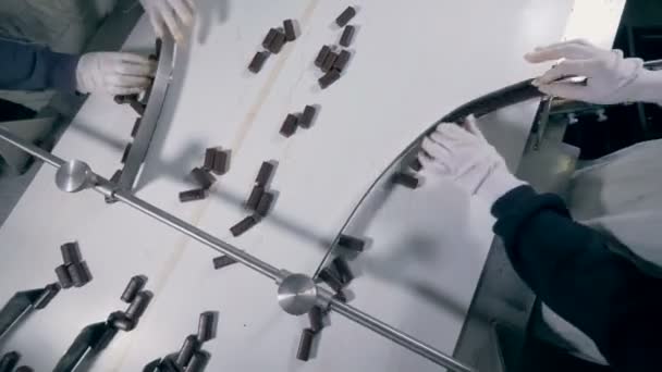 Två fabriksarbetare sorterar choklad godis som sedan går i olika riktningar — Stockvideo