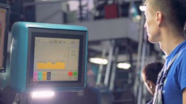 Mühendis dokunmatik bir endüstriyel makine kullanarak fabrika donanım seçenekleri seçer.